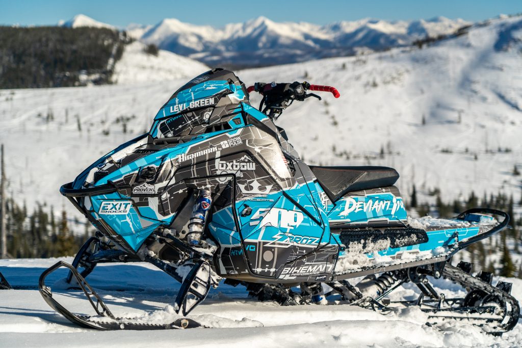 Snowmobile wrapped in custom Deviant Ink graphics for Levi Green, captured in a snowy mountain backdrop