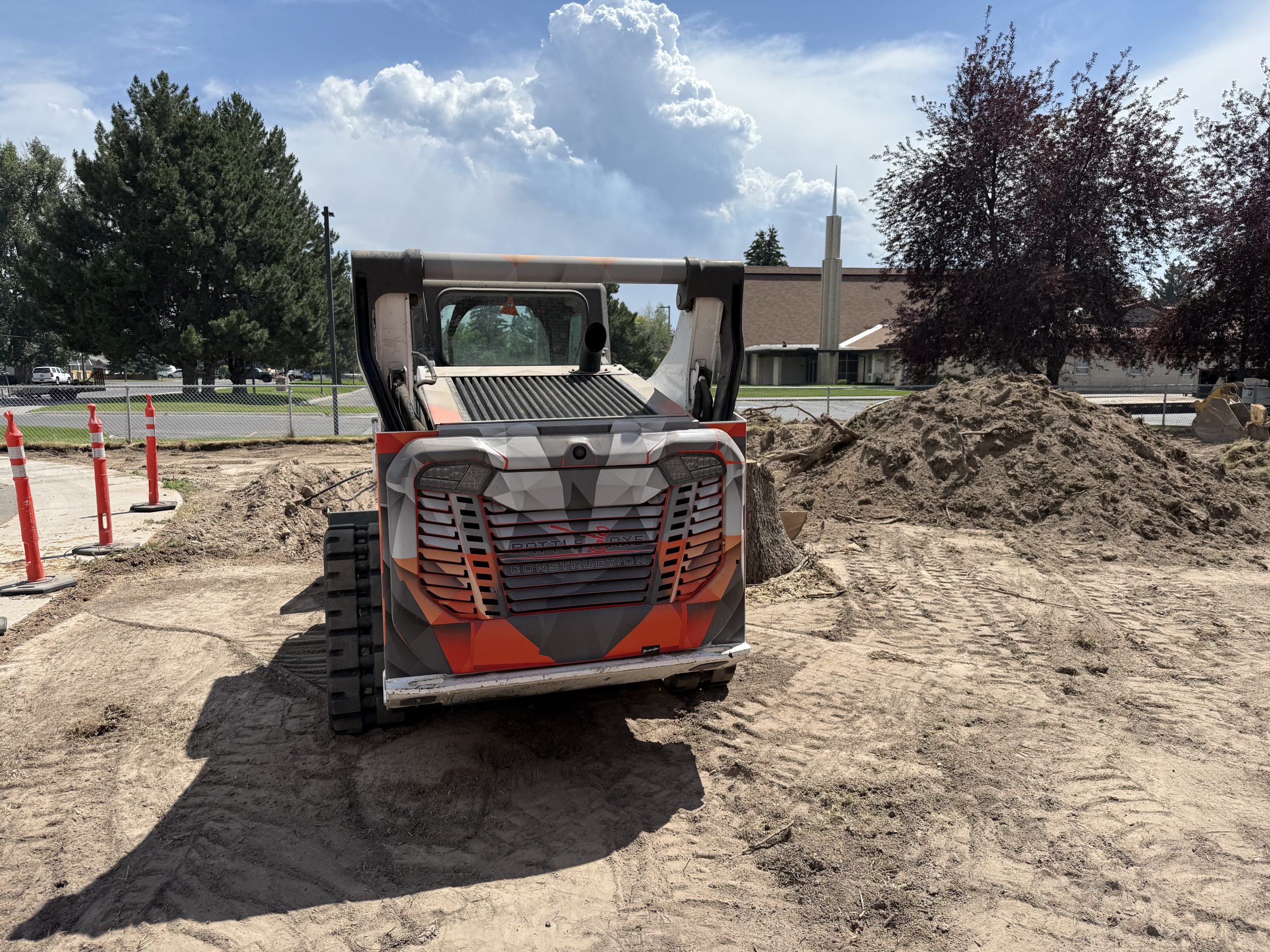 Rear view of custom-wrapped Bobcat skid steer in orange and grey Battle Axe Construction design by Deviant Ink