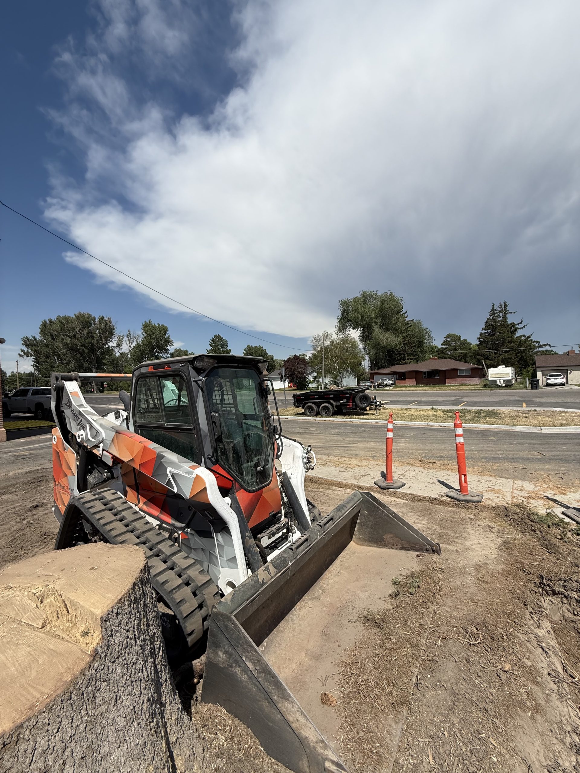 Front-side view of Bobcat skid steer with orange and grey Deviant Ink wrap for Battle Axe Construction