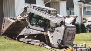 Custom-wrapped Bobcat T66 lifting dirt on a sloped residential lawn, wrapped by Deviant Ink
