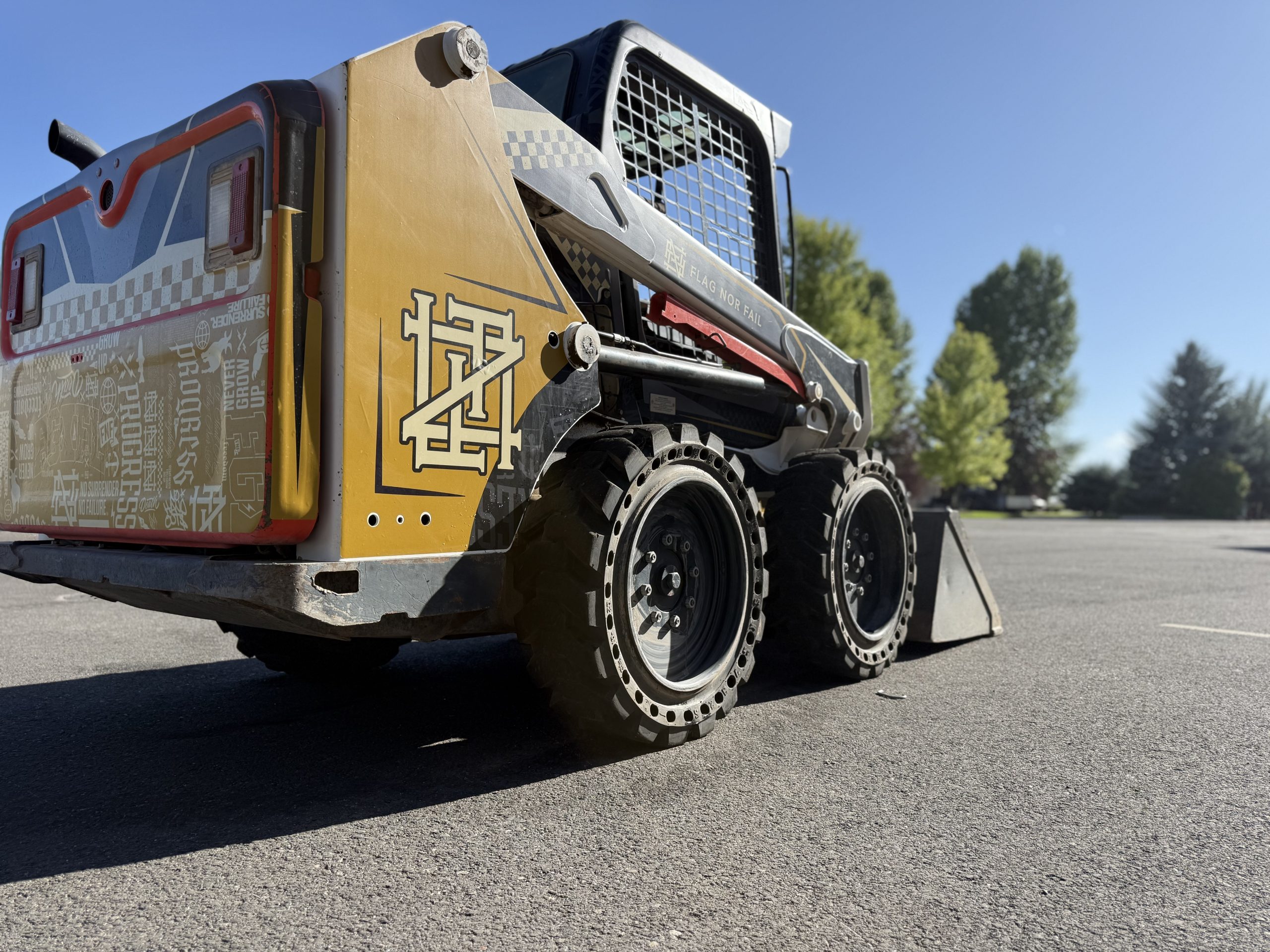 Custom-designed Bobcat S510 wrap by Deviant Ink for Rob Bailey, featuring Flag Nor Fail branding, yellow and grey tones, and heavy-duty solid tires