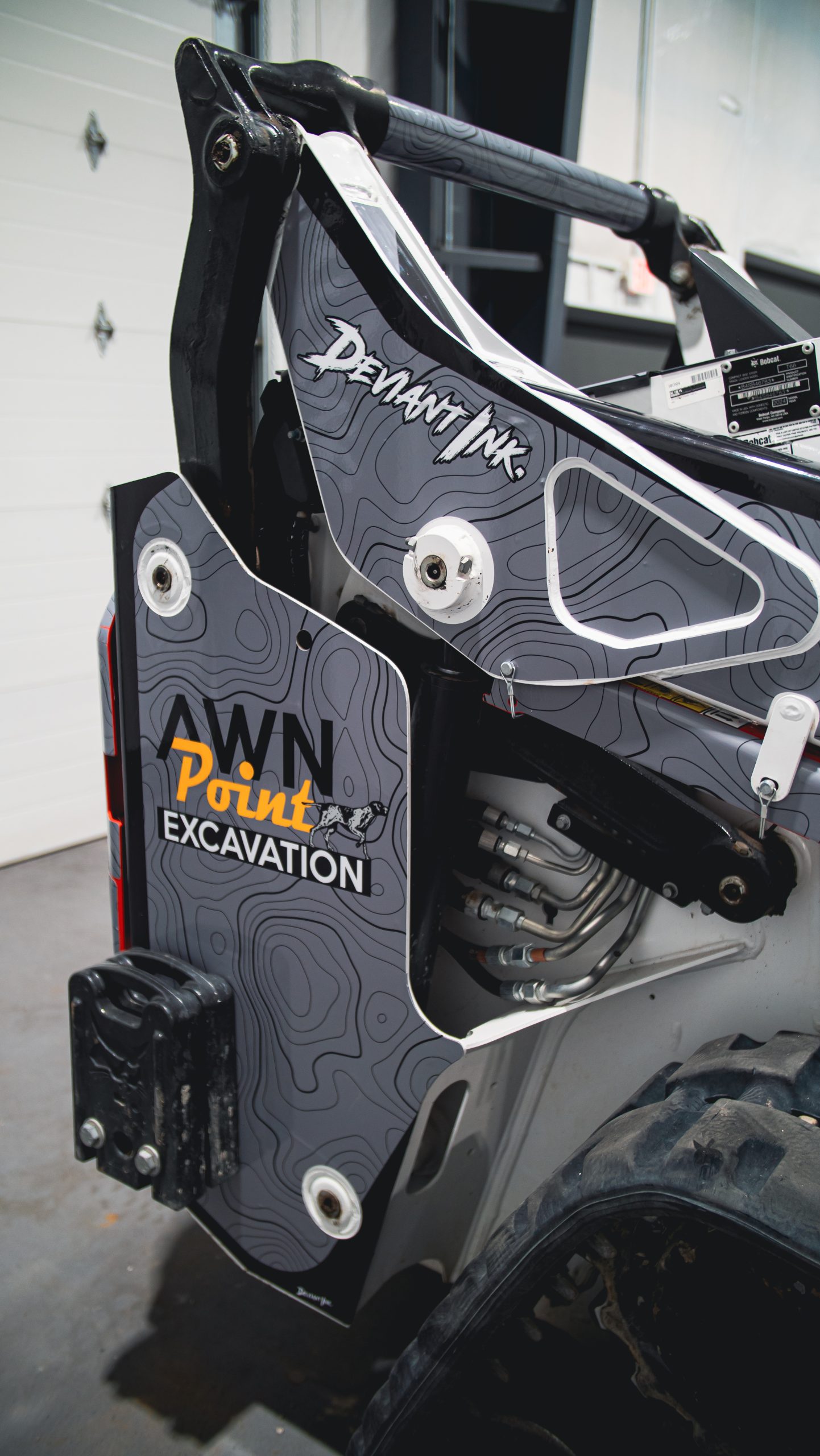 Close-up of a Bobcat T66 featuring the Elevation design wrap by Deviant Ink with contour-line styling and custom branding for Awn Point Excavation