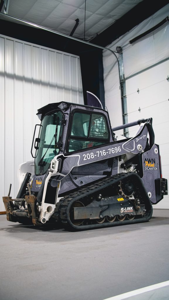 Full side view of a Bobcat T66 featuring the Elevation topographic wrap by Deviant Ink for Awn Point Excavation, including company phone number on the arm