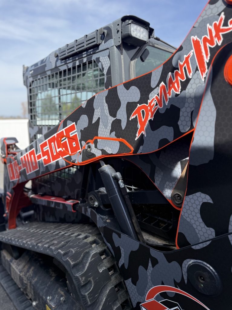 Side view of Kubota skid steer with true camo vinyl wrap by Deviant Ink